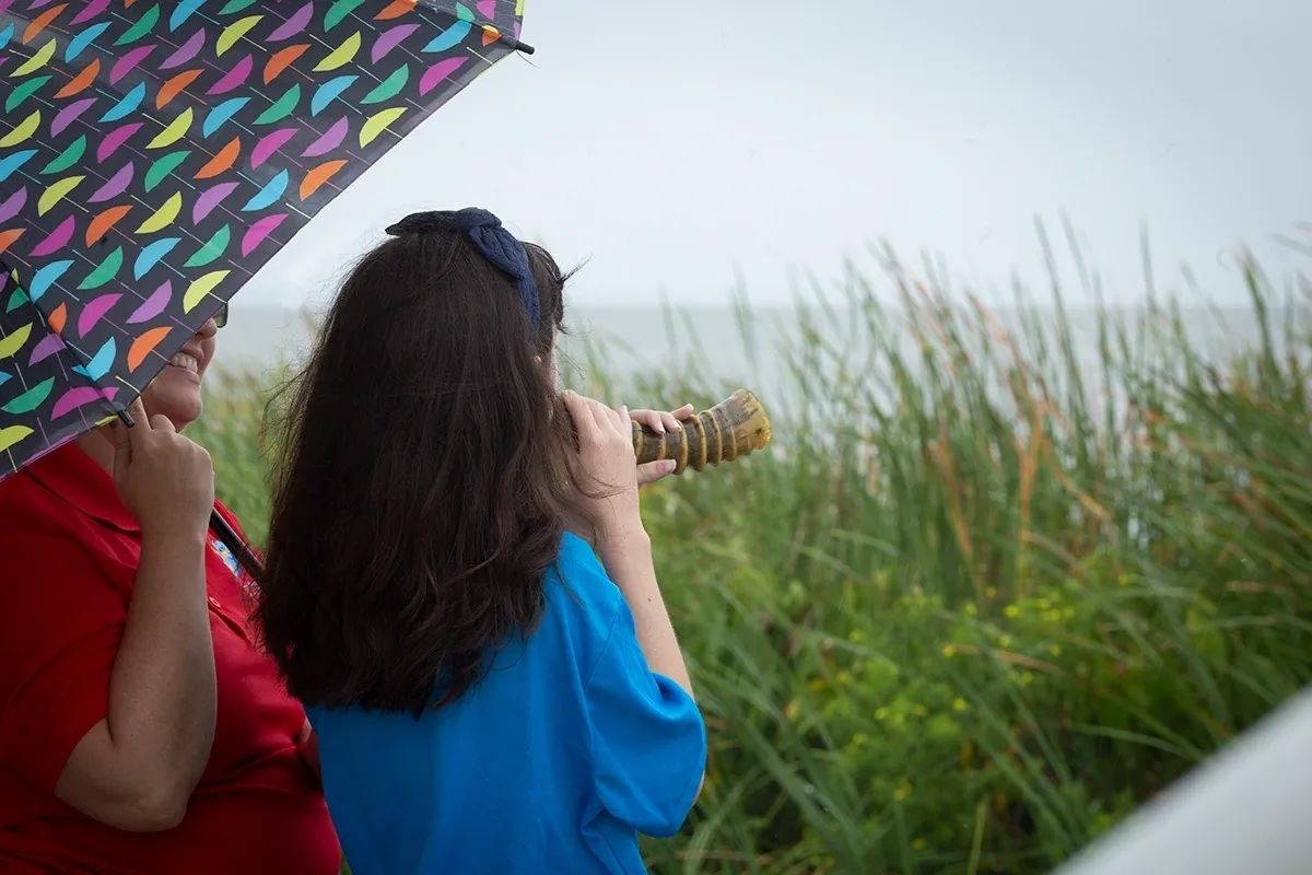 A woman holding an umbrella and taking pictures.