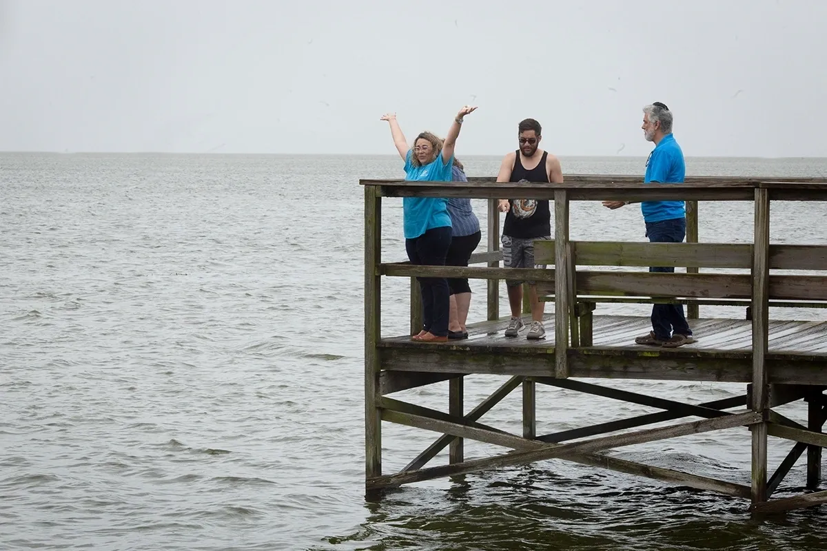 A group of people standing on top of a wooden pier.