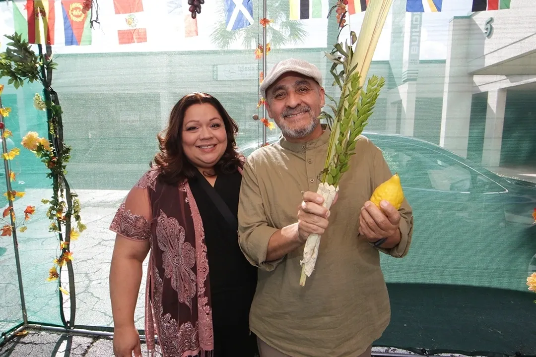 A man and woman holding up a vegetable.