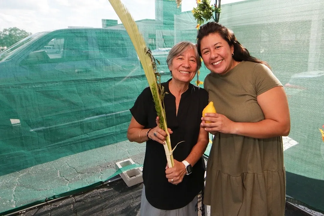 Two women holding a banana and a leaf.