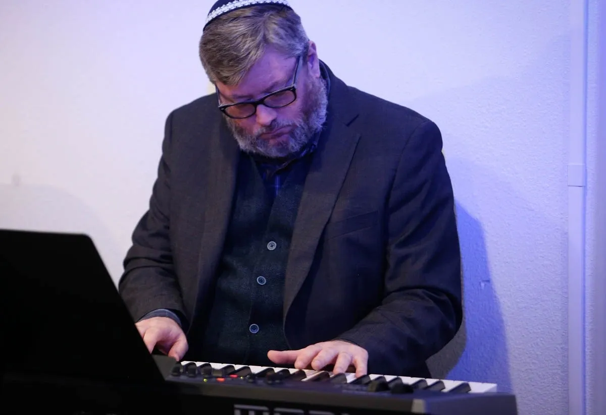A man in glasses and a suit playing the piano.