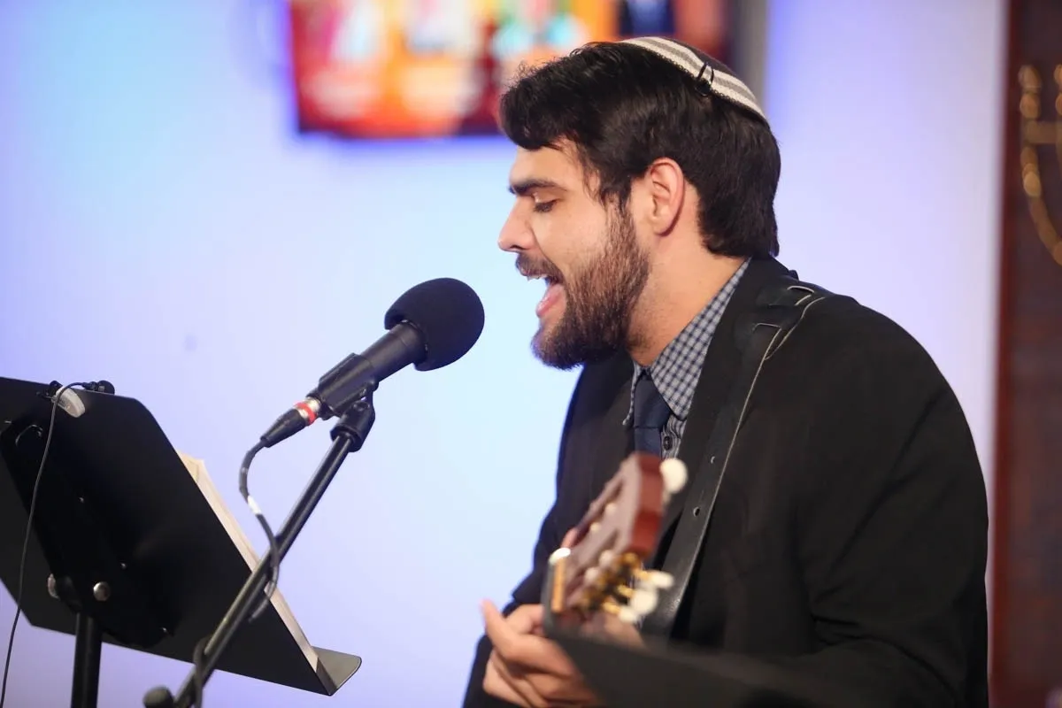A man singing into a microphone while holding a guitar.