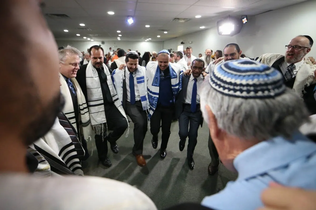 A group of men in blue and white robes walking down the hall.
