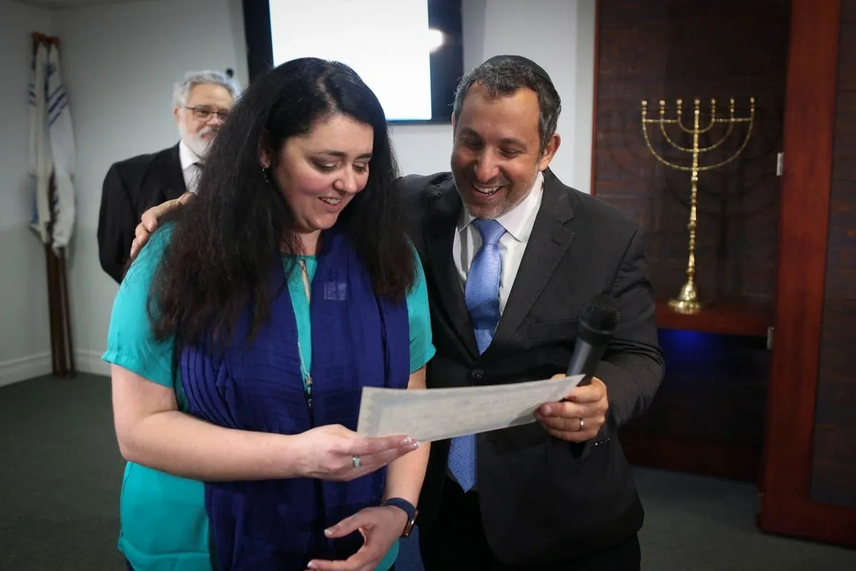 A man and woman looking at papers in front of a menorah.