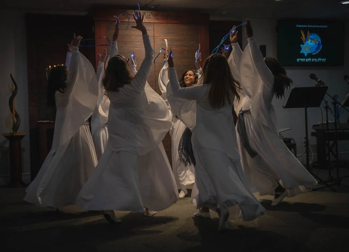 A group of people in white dresses dancing.