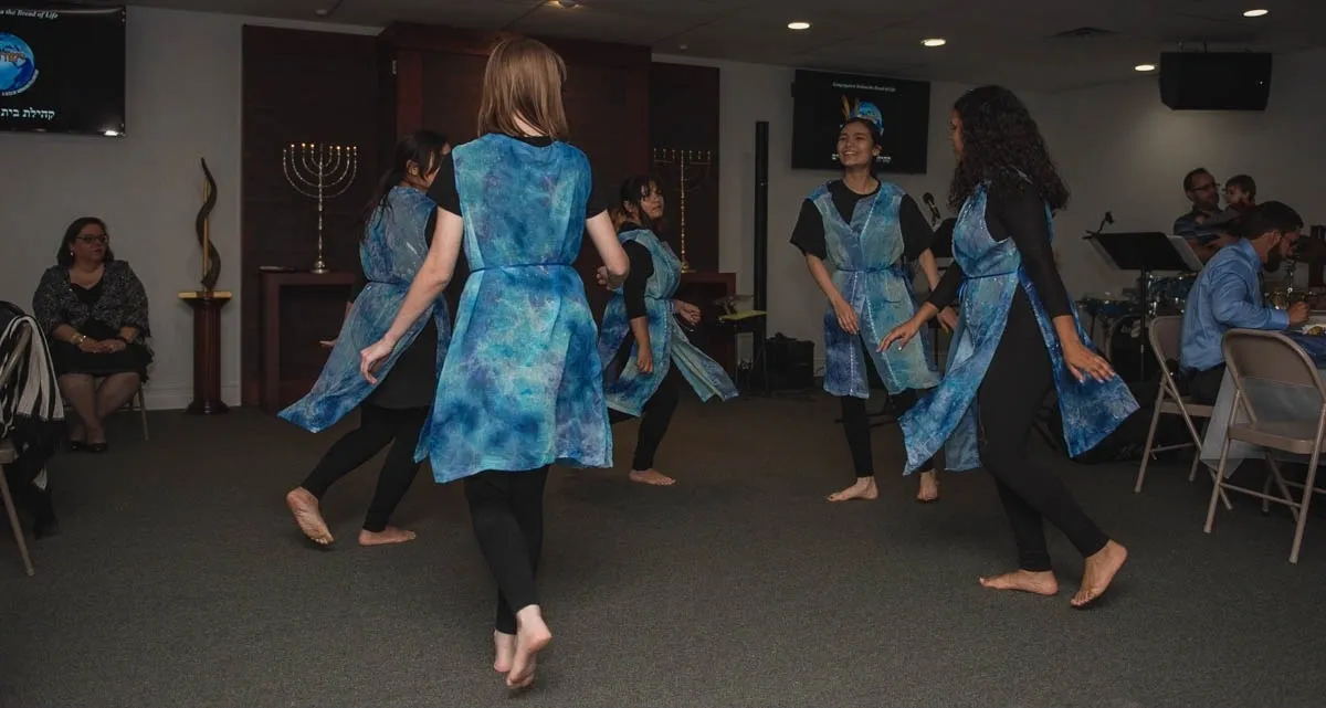 A group of people in blue dresses dancing.